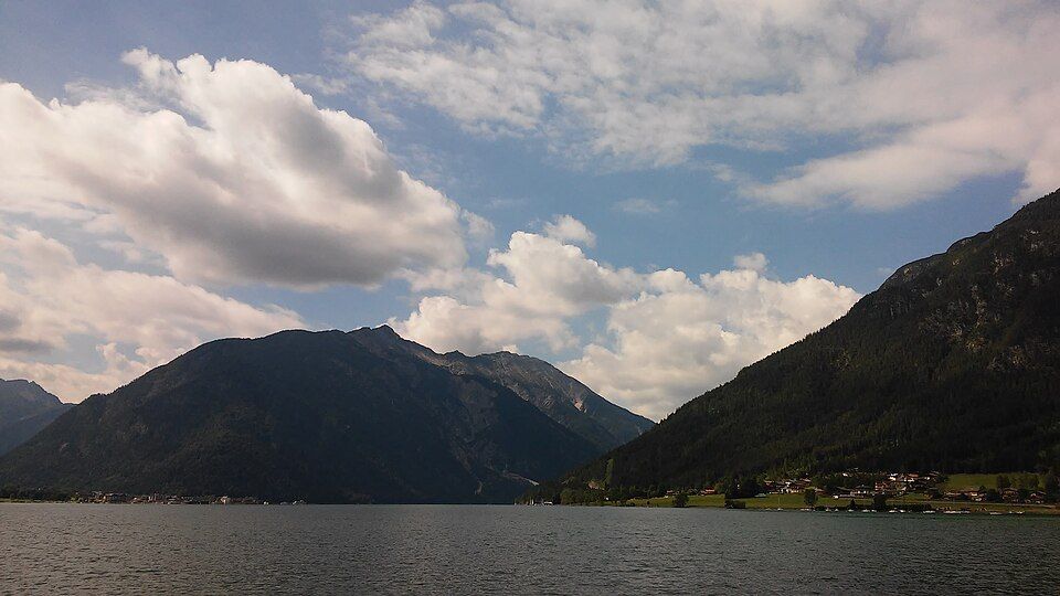 Panorama jezera Achensee s tyrkysovou vodou a horami kolem dokola