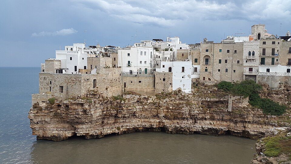 Pohled na Polignano a Mare z moře — bílá zástavba starého města nad vápencovými skalami