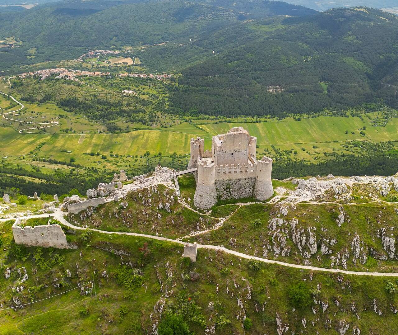 Letecký pohled na Rocca Calascio na horském hřebeni nad zeleným údolím