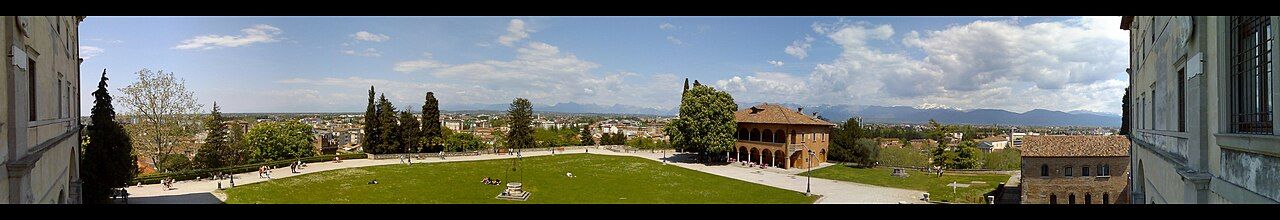 Panorama Udine s hradem na zeleném kopci nad střechami starého města