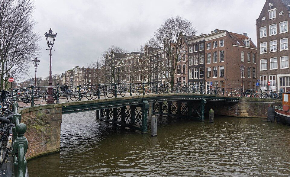 Zaparkovaná kola u zábradlí mostu nad amsterdamským kanálem