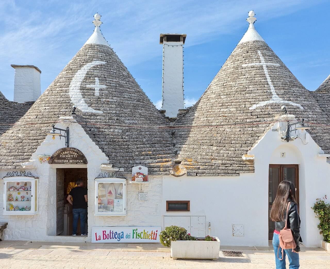 Kuželové domky trulli s bílými symboly na střechách v Alberobellu