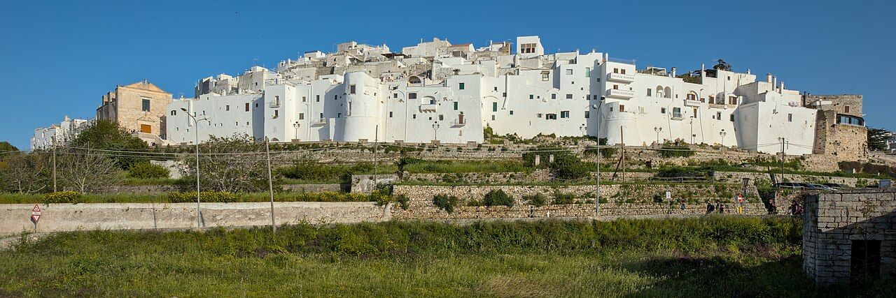 Bílé město Ostuni zářící na kopci nad olivovými háji