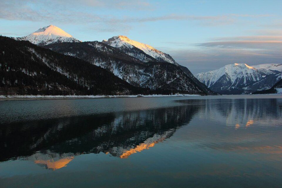 Achensee s loděmi u břehu a horami v pozadí