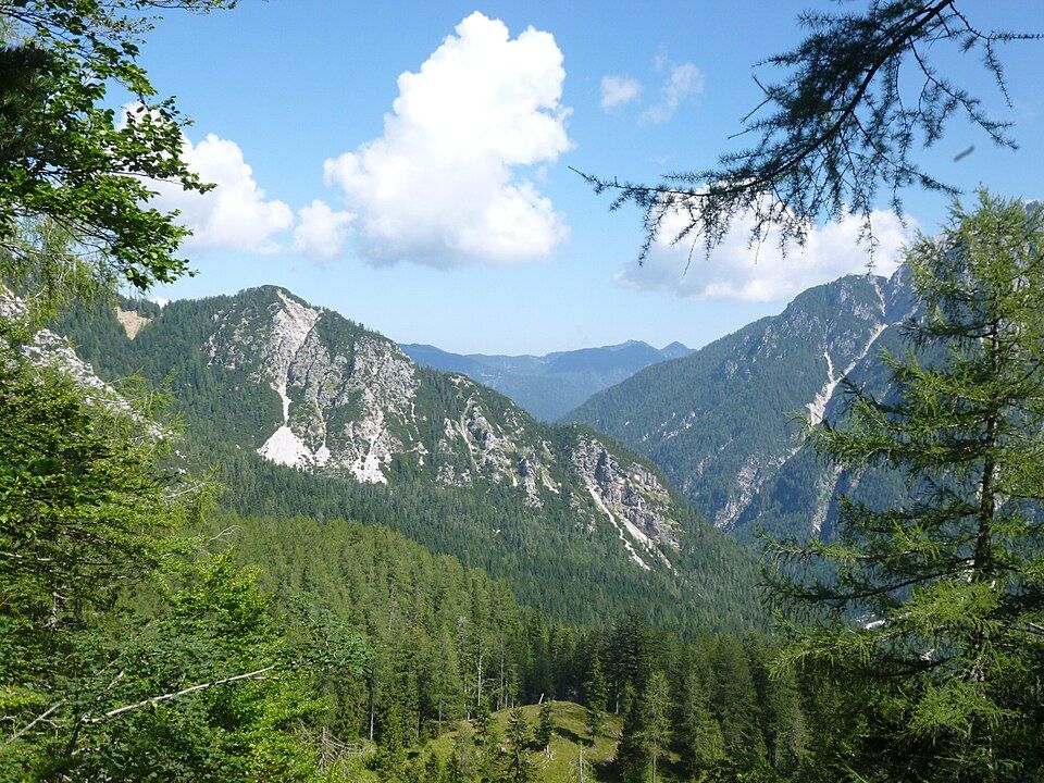 Stoupání na průsmyk Vršič — klikatá silnice přes zelené alpské svahy