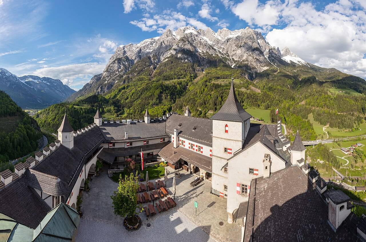 Hrad Hohenwerfen na skále nad údolím s alpskými štíty v pozadí
