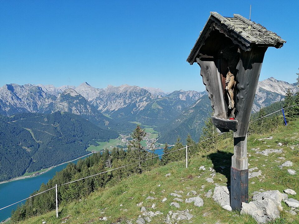 Dřevěný kříž nad jezerem Achensee s výhledem na vodu a hory