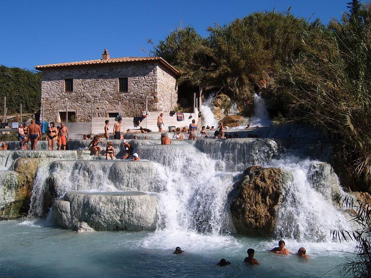Saturnia — bílé travertinové kaskády Cascate del Mulino s tyrkysovou termální vodou pod starým mlýnem