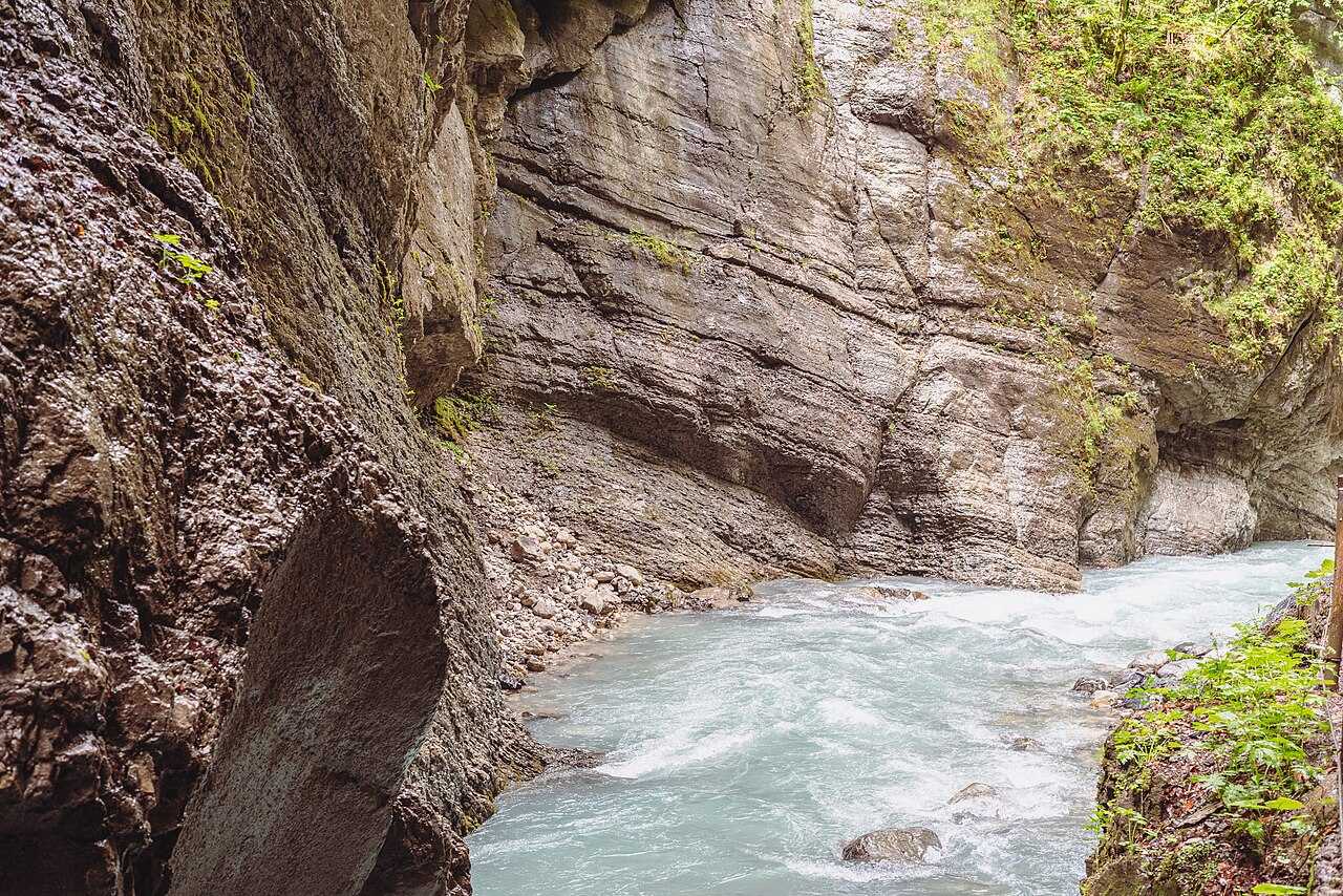 Úzká stezka soutěskou Partnachklamm vytesaná do skály nad bouřící řekou