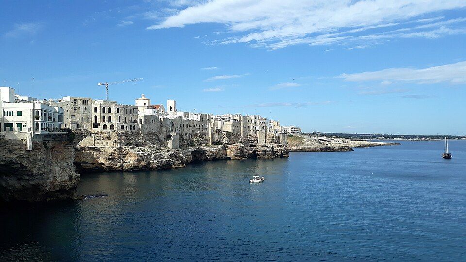 Panoramatický pohled na Polignano a Mare — bílé domy starého města na vápencových útesech nad mořem
