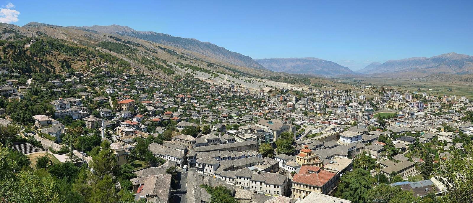 Panorama kamenného města Gjirokastër v údolí řeky Drino, nad kempem