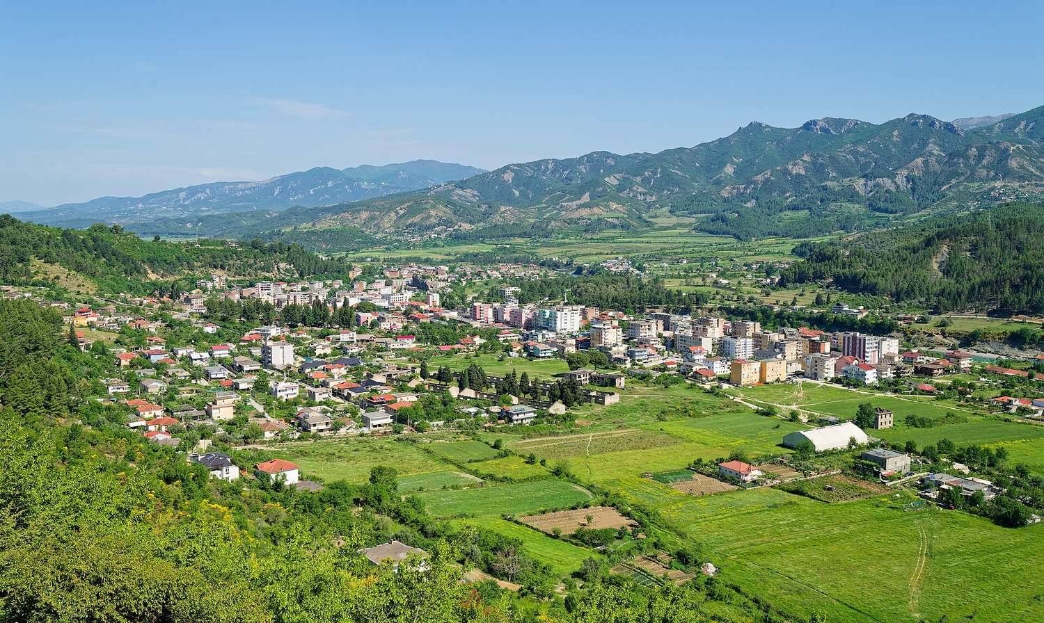 Zelené údolí kolem Përmetu s poli a horami, kde leží ekokemp