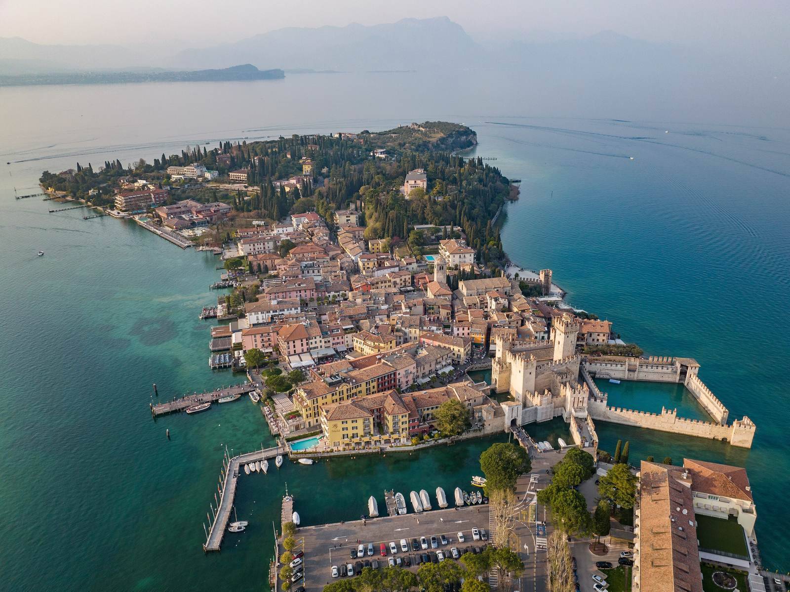 Letecký pohled na poloostrov Sirmione na Lago di Garda — staré město s hradem Scaligerů obklopené tyrkysovou vodou