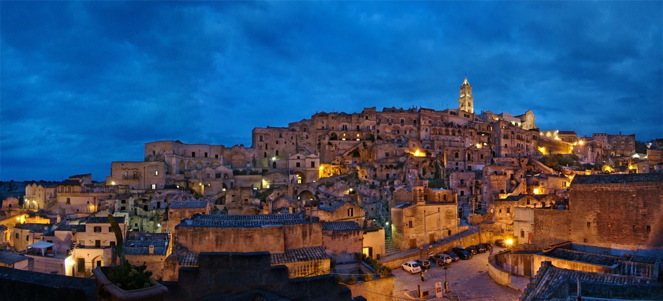 Večerní pohled na skalní čtvrti Sassi di Matera s rozsvícenými kamennými domy