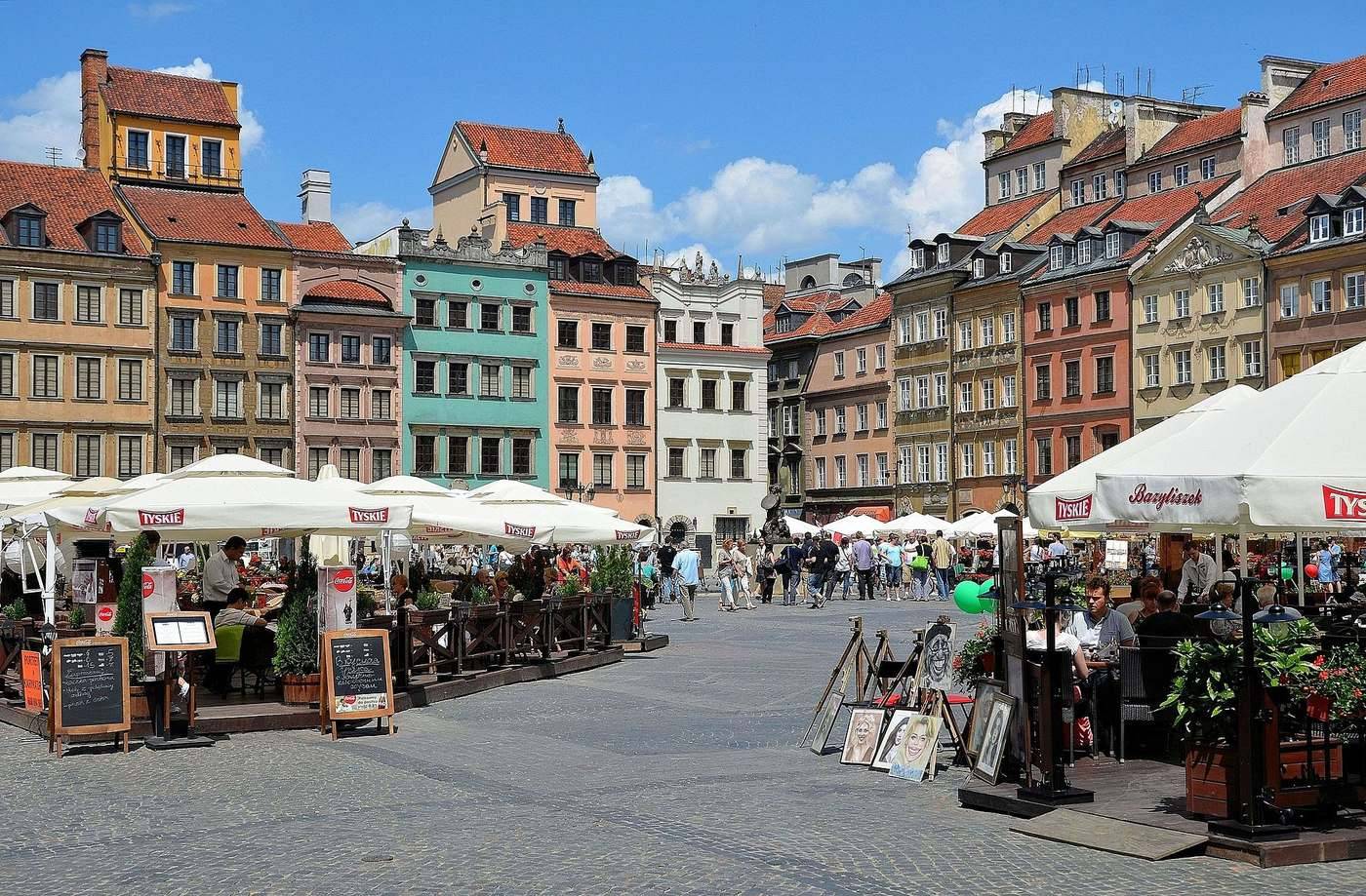 Restaurační zahrádky a stánky na Rynku Starego Miasta ve Varšavě pod malovanými fasádami domů